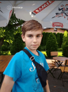 a boy in a blue shirt stands under an umbrella that says samiec on it