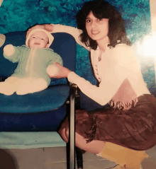 a woman holding a baby in a blue chair