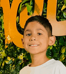 a young boy smiles in front of a sign that says " you "