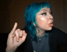 a woman with blue hair is making a rude gesture with her middle finger