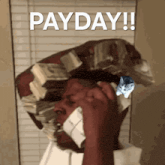 a man with a stack of money on his head is talking on a cell phone
