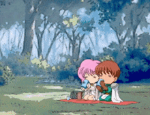 a boy and a girl are sitting on a blanket in a field