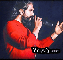 a man with a beard is singing into a microphone with yash.ae written on the bottom right