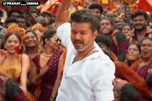 a man in a white shirt is standing in front of a crowd with his arm in the air ..