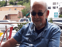 a man wearing sunglasses is sitting in front of a building that says new south educational centre