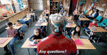 a man in a superhero costume is standing in front of a classroom full of children and asking any questions