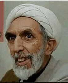 a man with a beard wearing a white turban and smiling .