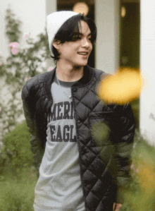 a young man wearing a black jacket and a grey shirt that says ameri eagle