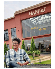 a young man sits in front of a habitat restaurant