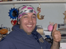 a man wearing a bandana giving a thumbs up sign