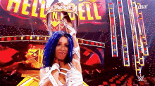 a woman with blue hair is holding a crown in front of a crowd .