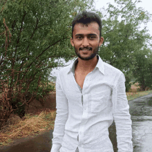 a young man in a white shirt is standing on a wet road