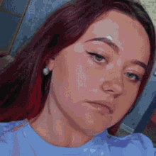 a woman with red hair and green eyes is wearing a blue shirt