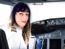 a woman in a pilot 's uniform is sitting in a cockpit