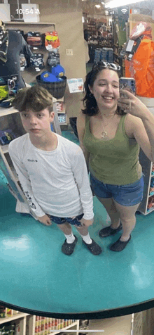 a man and a woman are taking a selfie in front of a mirror in a store