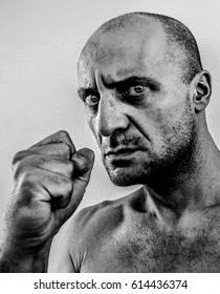 it is a black and white photo of a bald man with a fist in his hand .