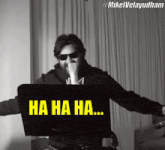 a man wearing sunglasses is laughing in front of a laptop screen that says ha ha ha