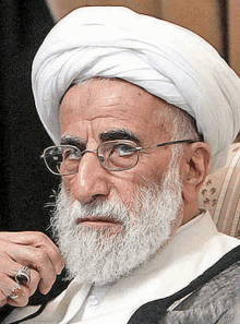 an older man with a beard and glasses is wearing a white turban .