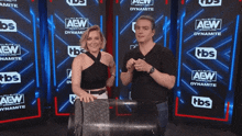 a man and a woman are standing in front of a wall that says aew
