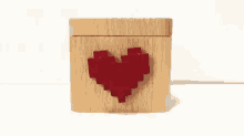 a wooden box with a red heart on it is sitting on a table .