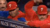 a group of baseball players wearing red hats with the letter p on them are sitting in the dugout .