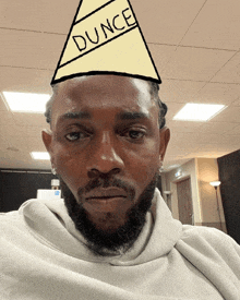 a man with a beard wears a party hat that says dunce