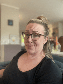 a woman wearing glasses and a black shirt looks at the camera