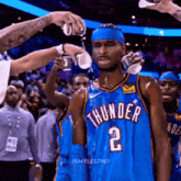 a basketball player with the number 2 on his jersey is getting water poured on his face .