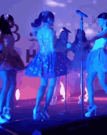 a group of girls are dancing on a stage in front of a microphone with the word uk in the background