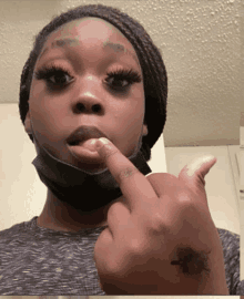 a woman wearing a face mask holds her finger to her mouth