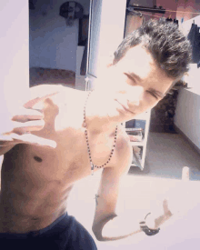 a shirtless young man with a necklace around his neck taking a selfie