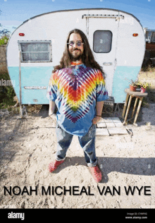 a man in a tie dye shirt is standing in front of a trailer with the name noah micheal van wye on the bottom