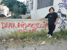 a man stands in front of a wall that has the word denk written in red