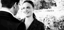 a black and white photo of a man and woman looking at each other .