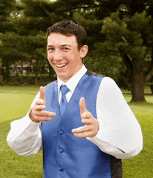 a man in a blue vest and white shirt is pointing