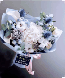 a bouquet of flowers is wrapped in blue paper with a pink ribbon and a tag that says ' a ' on it