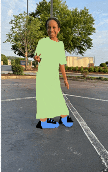 a little girl in a green dress and blue shoes is standing in a parking lot