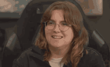 a woman wearing glasses and a black jacket is smiling for the camera