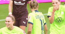 a group of female soccer players are standing on a field . one of the players is wearing a number 1 jersey .