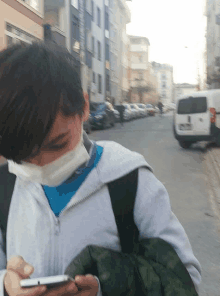 a boy wearing a mask looks at his cell phone