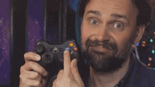 a man with a beard is holding an xbox 360 controller