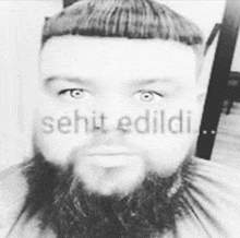 a black and white photo of a man with a beard and the words şehit edildi