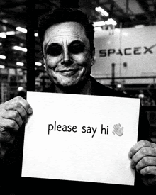 a man with black eyes is holding a sign that says please say hi