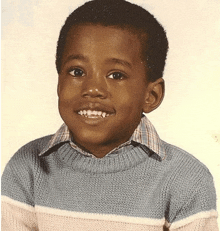 a young boy wearing a blue and white sweater smiles for a picture