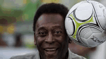 a man is holding a soccer ball on his head and smiling .