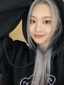 a woman with gray hair wearing a black hoodie with a heart on it