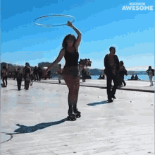 a woman is spinning a hula hoop while rollerblading on a sidewalk in front of a sign that says awesome