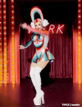a drag queen is dancing on a stage in front of a sign that says werk