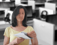 a woman in a yellow shirt holds a piece of paper