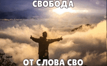 a man stands on top of a mountain with his arms outstretched in front of the clouds